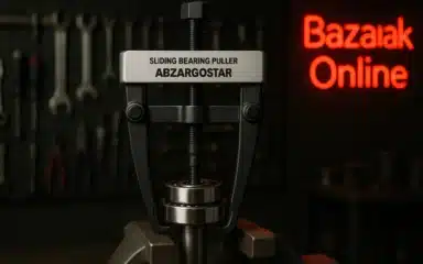 تصویری با وضوح بالا از ابزار کشنده بلبرینگ سرخوردنی (Sliding Bearing Puller) ساخت شرکت ابزارگستر (Abzargostar) که در مرکز قاب قرار دارد و در حال بیرون کشیدن یک بلبرینگ از روی شفت فلزی است. پس‌زمینه یک کارگاه صنعتی با نورپردازی متمرکز دیده می‌شود و دیوار پشت ابزار مملو از آچارها، پیچ‌گوشتی‌ها و سایر تجهیزات صنعتی است. در سمت راست تصویر یک تابلو نئون قرمز با نوشته «بازارک آنلاین» با فونت ساده قرار دارد. فضا حال و هوای صنعتی تاریک، دقیق و محیط کاری تمیز و حرفه‌ای را القا می‌کند.