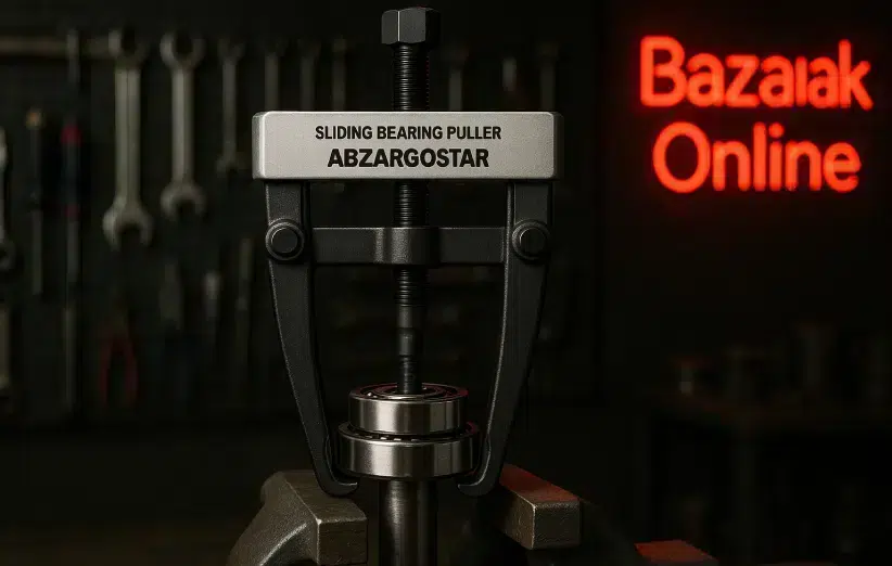 تصویری با وضوح بالا از ابزار کشنده بلبرینگ سرخوردنی (Sliding Bearing Puller) ساخت شرکت ابزارگستر (Abzargostar) که در مرکز قاب قرار دارد و در حال بیرون کشیدن یک بلبرینگ از روی شفت فلزی است. پس‌زمینه یک کارگاه صنعتی با نورپردازی متمرکز دیده می‌شود و دیوار پشت ابزار مملو از آچارها، پیچ‌گوشتی‌ها و سایر تجهیزات صنعتی است. در سمت راست تصویر یک تابلو نئون قرمز با نوشته «بازارک آنلاین» با فونت ساده قرار دارد. فضا حال و هوای صنعتی تاریک، دقیق و محیط کاری تمیز و حرفه‌ای را القا می‌کند.